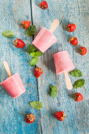 Strawberry sorbet with mint on a stick on a wooden table.の写真素材