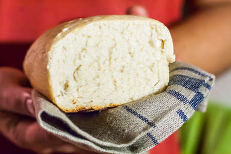 loaf of white fresh bread in the hands of men.