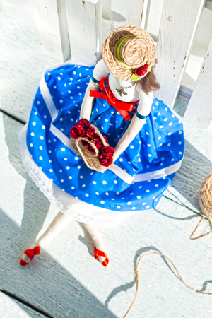 tilde doll in a blue skirt and a straw hat with a basket with flowers/の写真素材