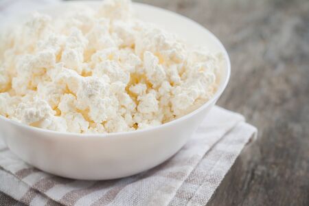 fresh cottage cheese in a white bowl on a wooden background.の写真素材