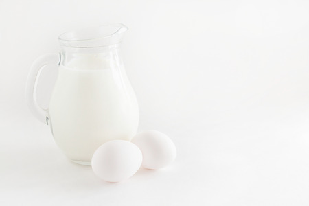 jug with milk and two eggs on white background.の写真素材