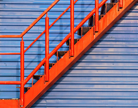 part of red fire escape on the blue wall.の写真素材
