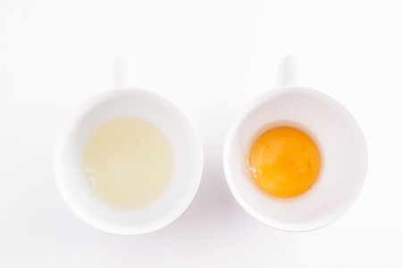 Chicken of raw white and yolk separately in a white bowl isolatedの写真素材