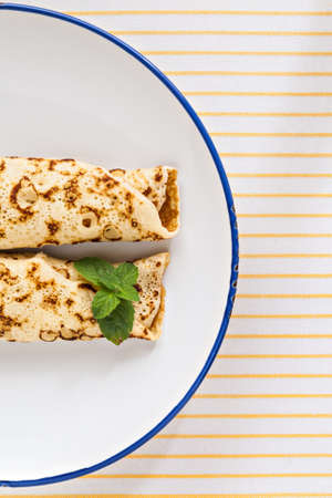 thin pancakes rolled crepes mint on a plate with knife and fork.