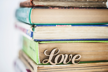 on a stack of old books wooden word love.の写真素材