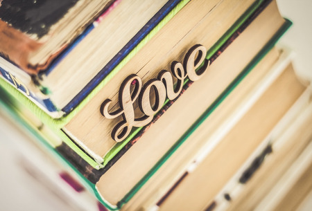on a stack of old books wooden word love.の写真素材