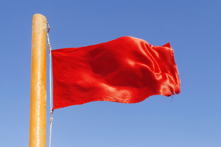 red flag to develop on the background of blue sky.の写真素材