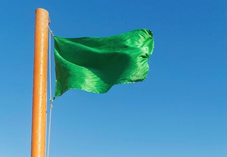 develop green flag on a background of blue sky.の写真素材
