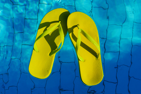 yellow flip-flops floating in a swimming pool, a top view.の写真素材