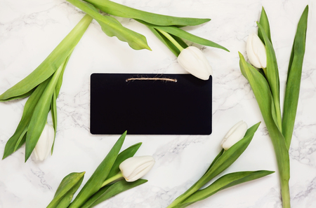 White tulips and chalkboard for notes on a marble gray background. Top view in retro, old styleの写真素材