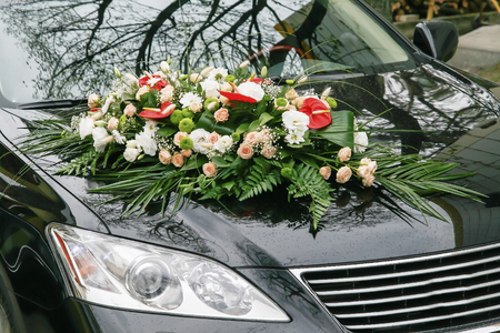 The hood of a black car is decorated with a bouquet of flowers in a wedding style.の写真素材