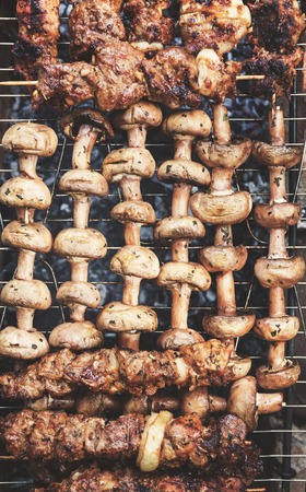 Meat-shish kebab and mushrooms on skewers and grill grill. Top view, close-up.の写真素材