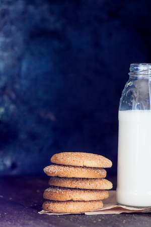 Bottle with milk and a stack of cookies on a dark background, retro style, vintage.の写真素材