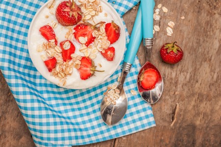 In a cup of yogurt, oat granola and fresh strawberries, on a bluの写真素材