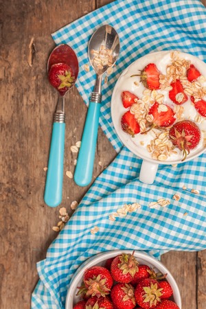 In a cup of yogurt, oat granola and fresh strawberries, on a bluの写真素材