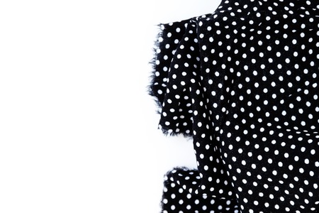 Piece of black fabric with a pattern of white peas, isolated on a white background.の写真素材