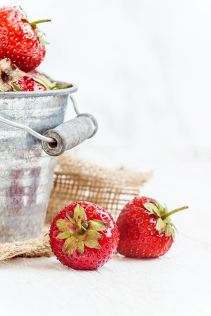 Fresh juicy strawberries in an old iron bucket on a white background.の写真素材