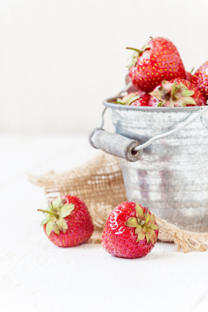 Fresh juicy strawberries in an old iron bucket on a white background.の写真素材