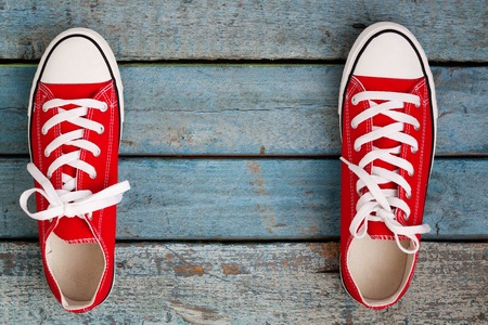 Red retro sneakers on a blue wooden background.の写真素材