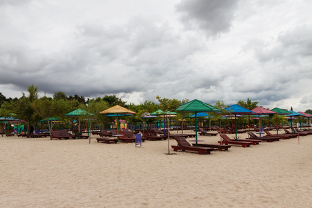 Empty beach with lots of sun loungers and umbrellas, against the background of a stormy sky.の写真素材