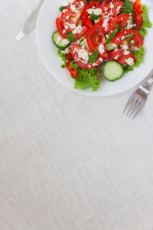 Shopska salad in a white plate on a white tablecloth. The concept of minimalism.の写真素材