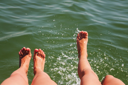 Two pairs of feet splash in the water.の写真素材