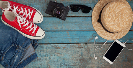 Still life of various items for recreation, clothing, hat, sneakers, camera, passport, telephone, sunglasses, tickets, headset on a wooden blue background. Concept of youth travel, light, economy.の写真素材