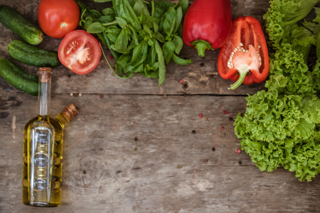 Raw ingredients of salad, tomato, cucumber, pepper, olive oil on a wooden background, top view and blank copy space for text.の写真素材