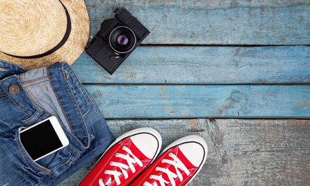 Still life of various items for recreation, clothing, hat, sneakers, camera, passport, telephone, sunglasses, tickets, headset on a wooden blue background. Concept of youth travel, light, economy.の写真素材