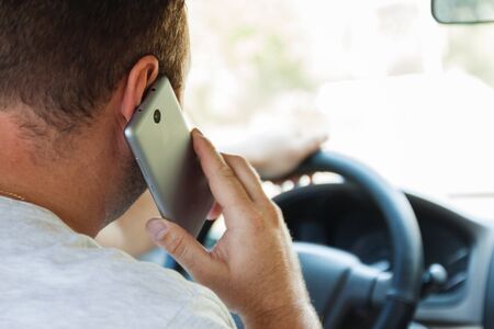man talking on a cell phone while driving a car.の写真素材
