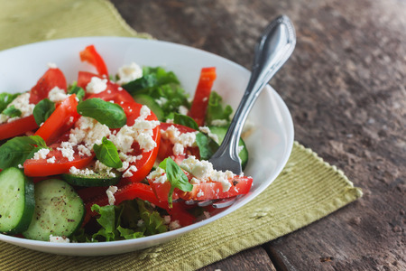 Shopska salad in a white plate on a wooden background, close-up.の写真素材