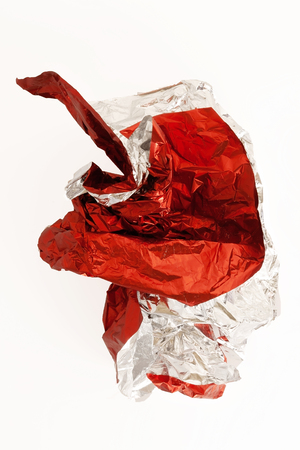 Crumpled wrapping paper ball falling on white surface.の写真素材