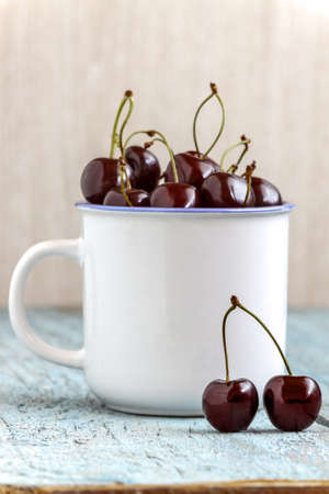 Cherries in the beautiful cup on wooden table, macro background, fruits, berries.の写真素材