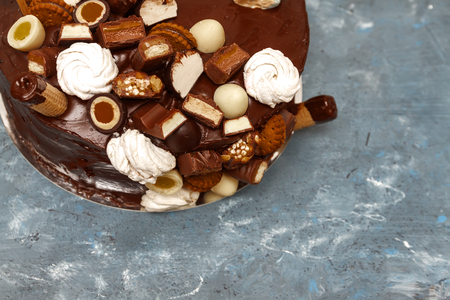 A festive chocolate cake decorated with a waffle horn, chocolate sweets, marshmallows, biscuits on a dark background.の写真素材