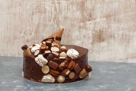 A festive chocolate cake decorated with a waffle horn, chocolate sweets, marshmallows, biscuits on a...