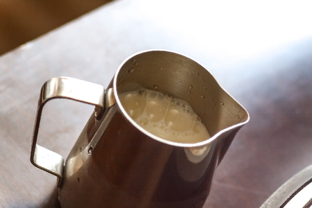 Barista pouring milk in to the jug. Man preparing milk and coffee. Coffee shopの写真素材