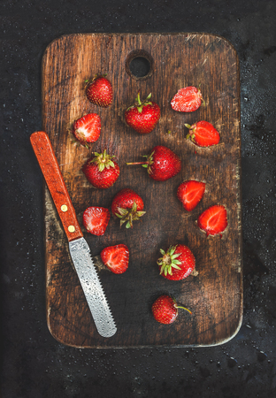 fresh juicy strawberries wooden board with knife on a dark background. Vintage retro toning.の写真素材