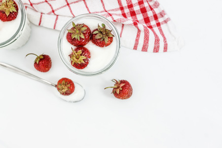 Dessert yogurt and strawberry layers in a glass on a red striped napkin on a white background.の写真素材