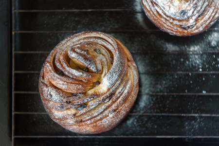 Cupcake pie crunch in the form of a roll sprinkled with powdered sugar on a dark background and an...
