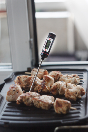 Pork-beef shish kebab prepared on a home electric grill.Thermometer for determining meat readiness and temperatureの写真素材