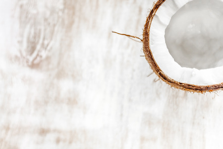 half coconut on a light white wooden background, closeup. Top view