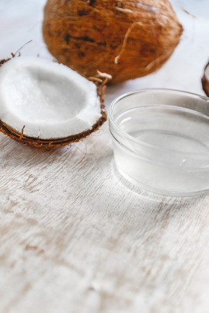 Whole coconut cut into chunks and chips and milk on a light white wooden background. Top viewの写真素材
