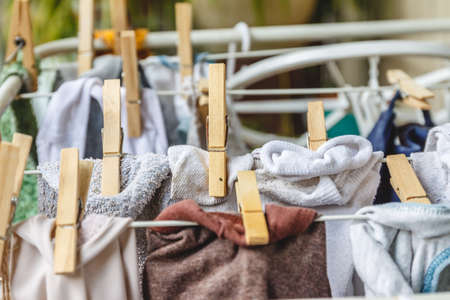 White and colored linen to be dried on the clothesline with wooden clothespinsの写真素材