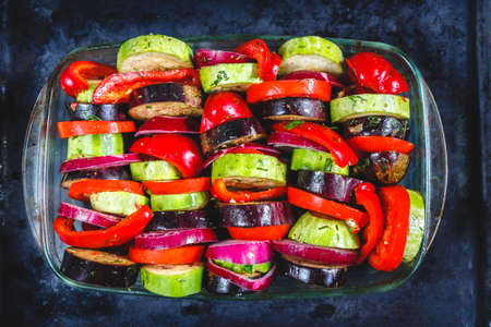 Assorted different bright and juicy baked vegetables, zucchini, eggplant, zucchini, tomato, pepper, onion on a dark retro background. The concept of healthy proper healthy vegan food. View from aboveの写真素材