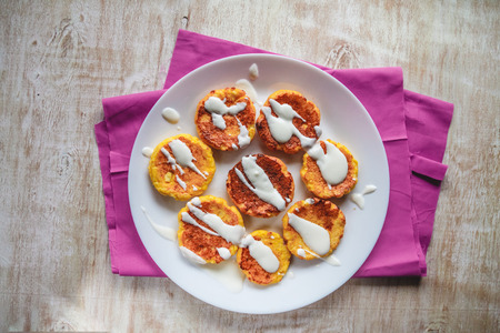 Curd cheesecakes, pancakes with sour cream on a plate and a light background. Top view. Close-up
