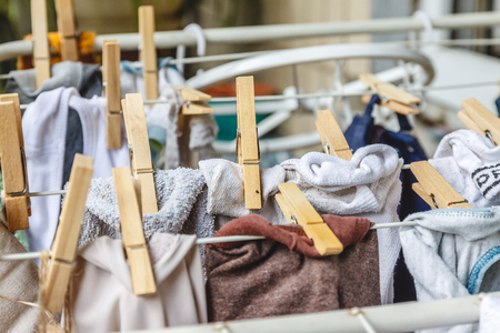 White and colored linen to be dried on the clothesline with wooden clothespins