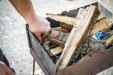 A man kindles a fire in a brazier with matches.