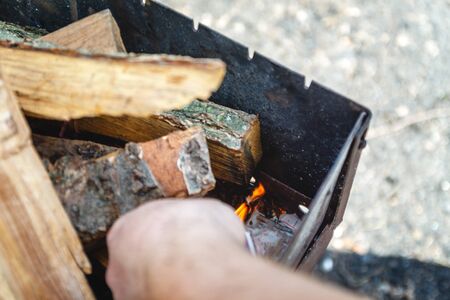A man kindles a fire in a brazier with matches.の写真素材