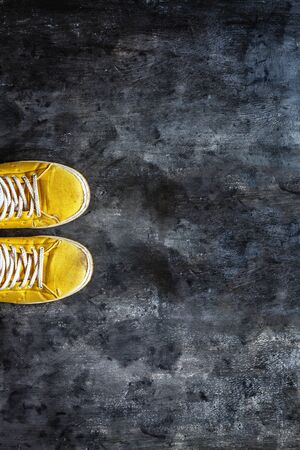yellow-orange sneakers with untied laces on a dark concrete background. Copy space. Top view.の写真素材