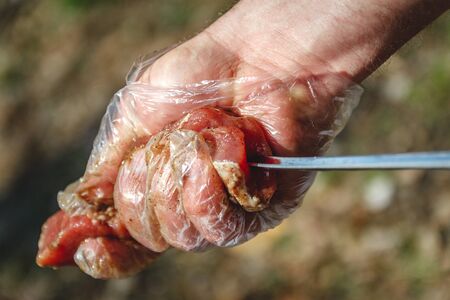 man stringing meat on a skewer. Close-up